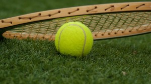 Tennis ball and grass court with wooden racquet